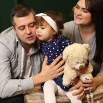 a man, woman and child sitting in front of a christmas tree